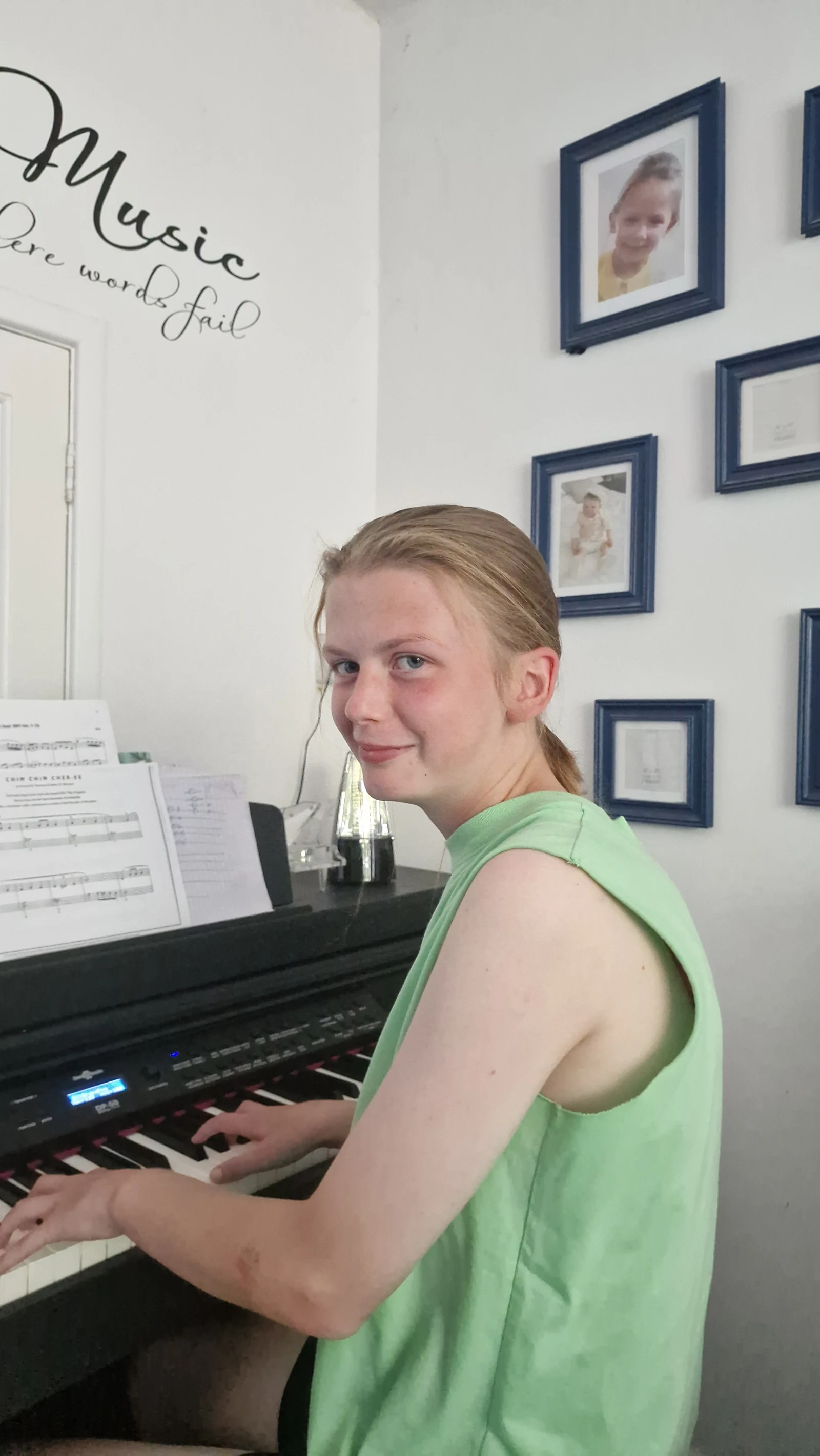 A young piano pupil learning at her digital keyboard at home, with sheet music in front of her