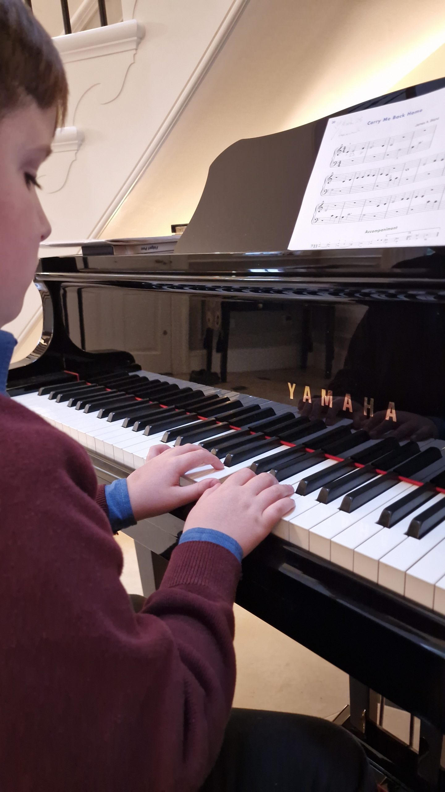 Child playing Yamaha piano during a home piano lesson in Derby